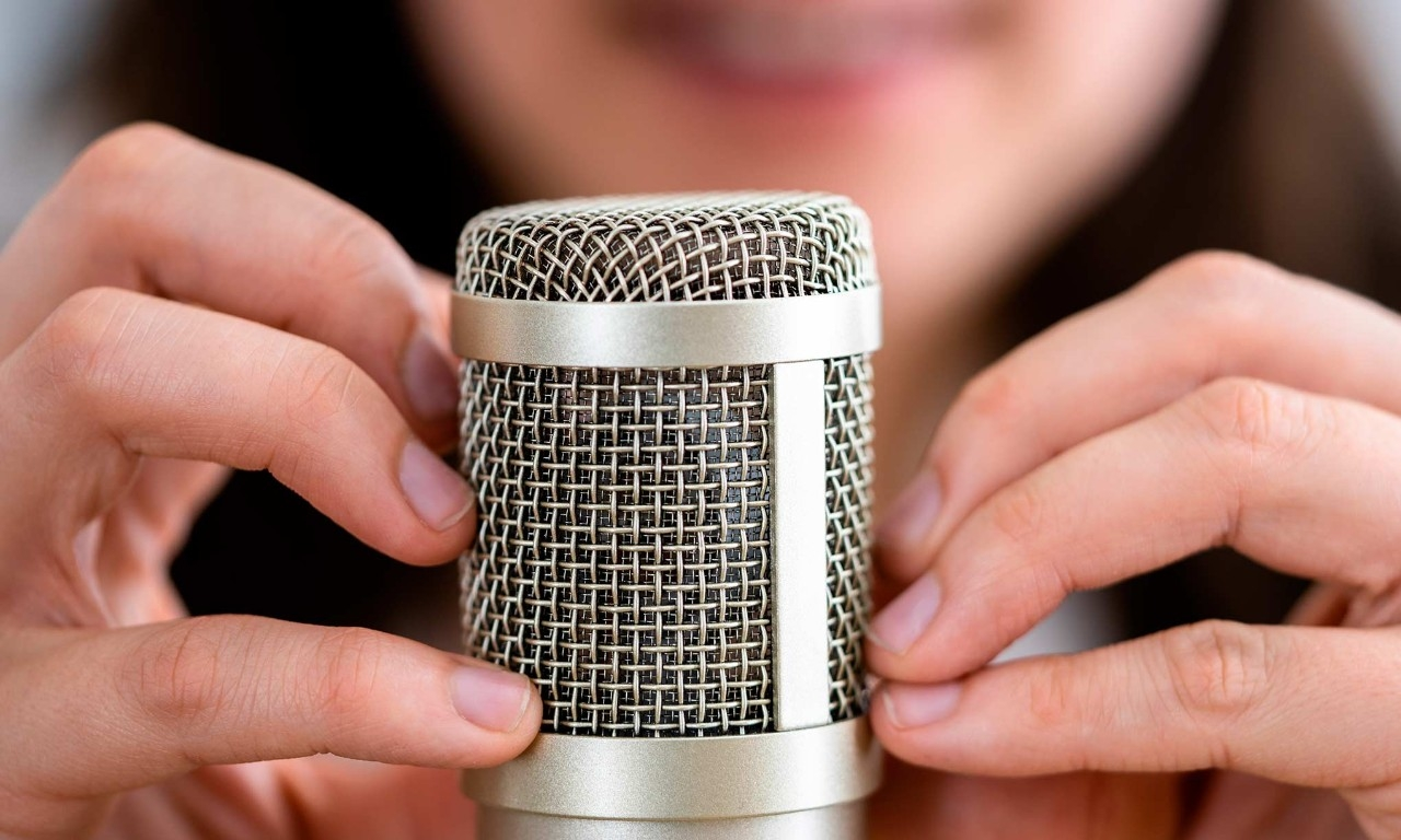 Hands gently touching a condenser microphone — a common ASMR trigger